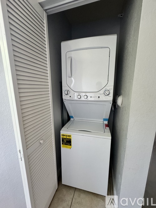 A white dryer is in a small closet.