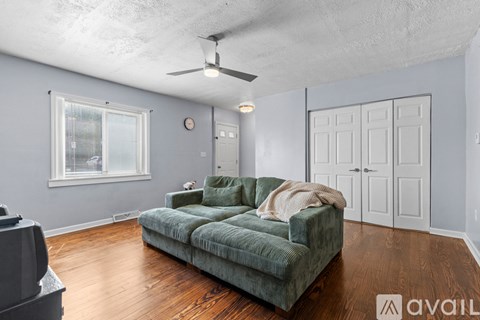 A living room with a green couch and a fan on the ceiling.