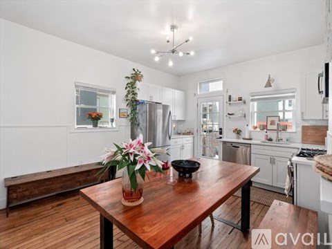 A kitchen with a wooden table and a vase of flowers on it.