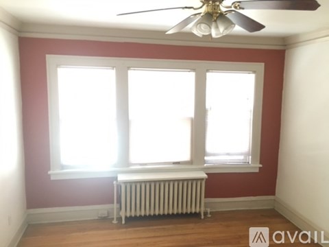 A room with a ceiling fan and two windows.