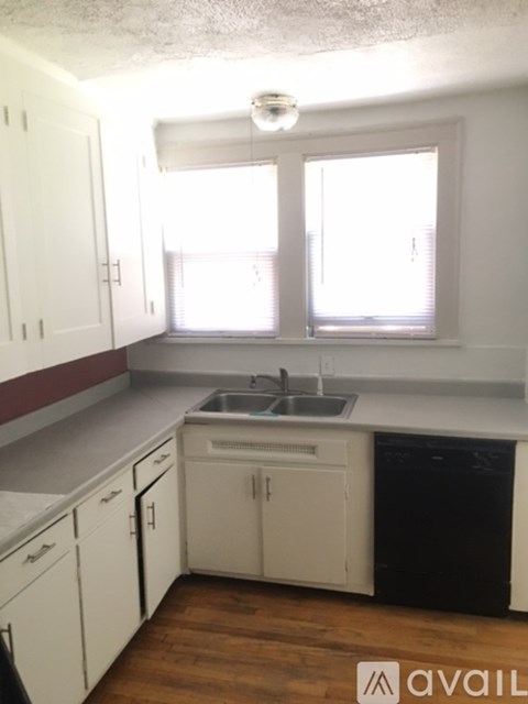A kitchen with white cabinets and a black dishwasher.