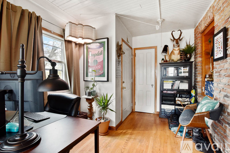 A room with a desk, chair, and a fireplace.