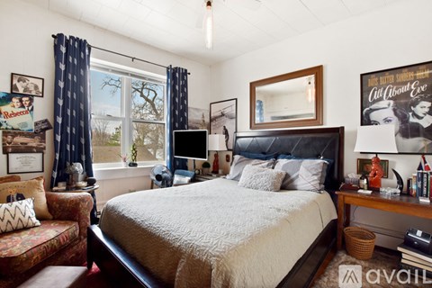 A bedroom with a large bed and a window with curtains.