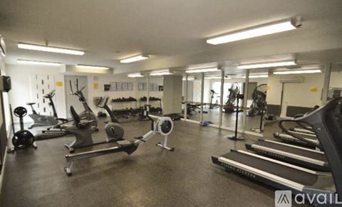 A gym with a variety of equipment including treadmills, weights, and exercise machines.