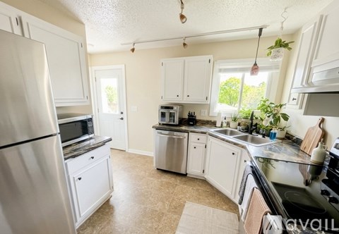 A kitchen with white cabinets and appliances.