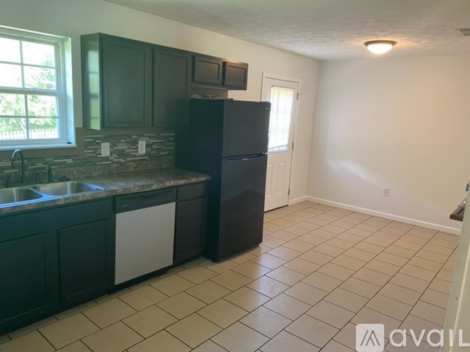 A kitchen with dark brown cabinets and a black refrigerator.