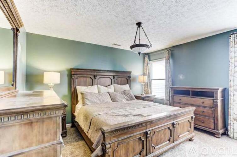 A bedroom with a large bed and a dresser.