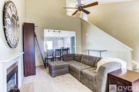 A living room with a grey couch and a fireplace.