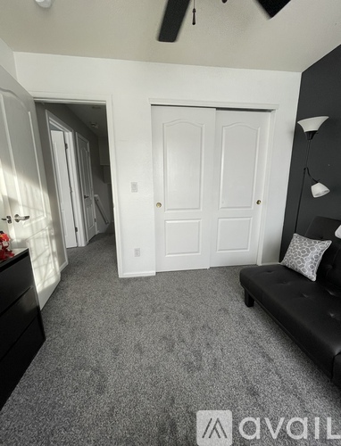 A living room with a black couch and a white door.