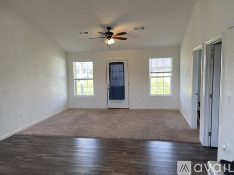 A spacious room with a ceiling fan and a door with a window above it.