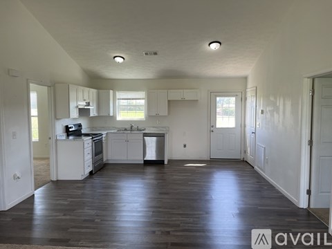 A kitchen with white cabinets and a wooden floor.