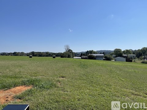 A field with a clear blue sky and some buildings in the distance.