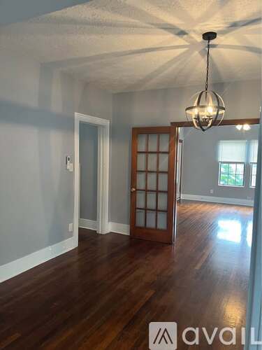 A room with wooden floors and a chandelier hanging from the ceiling.