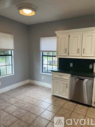 A kitchen with white cabinets and a black countertop.