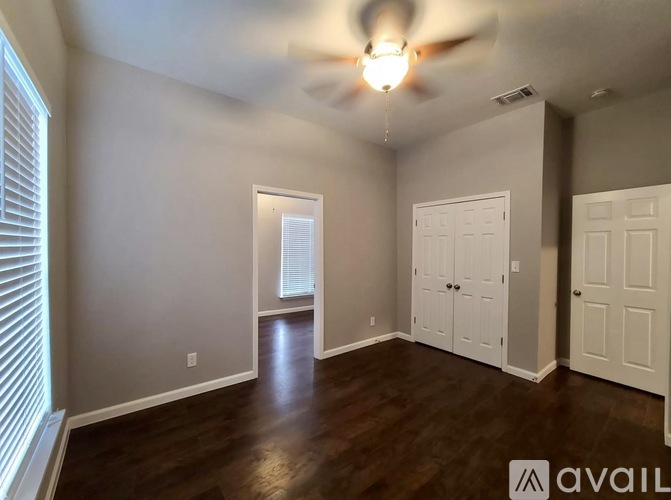 A room with a ceiling fan and wooden floors.