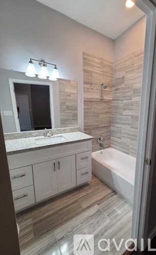 A bathroom with a sink, mirror, and bathtub.