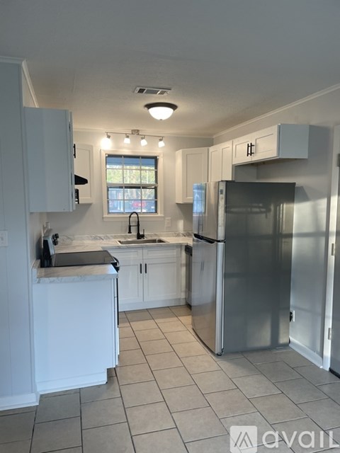 A kitchen with white cabinets and a stainless steel refrigerator.