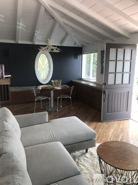 A living room with a grey couch and a round window.