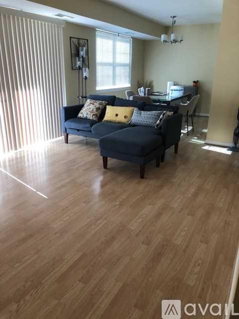 A living room with a blue couch and wooden flooring.