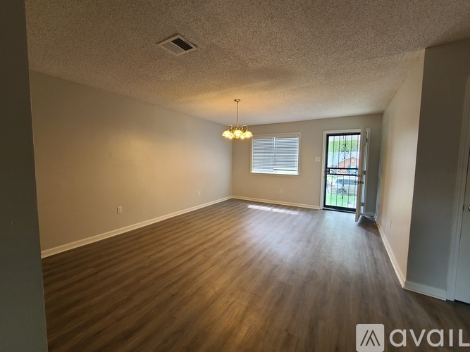 A room with wooden flooring and a chandelier hanging from the ceiling.