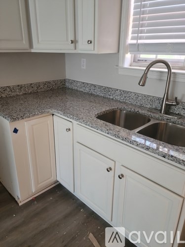 A kitchen with white cabinets and a granite countertop.