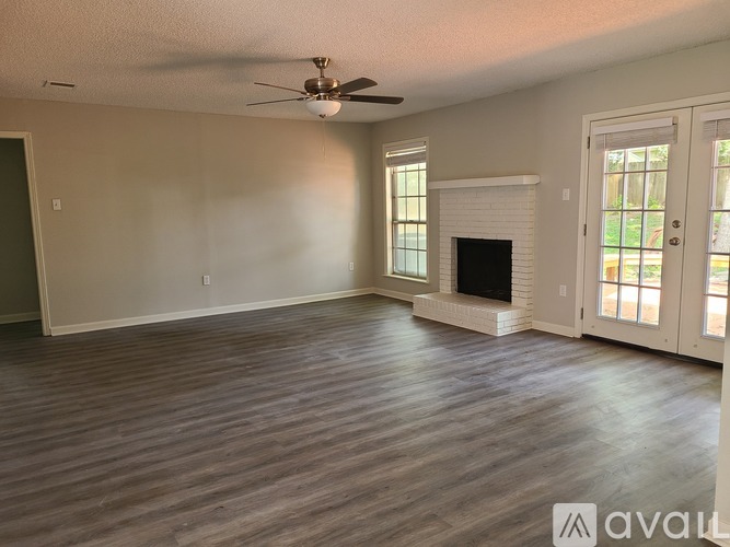 A spacious living room with a fireplace and a ceiling fan.