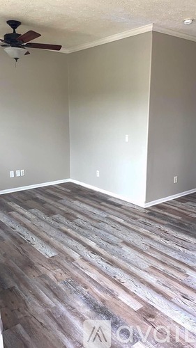 A room with a ceiling fan and wooden flooring.
