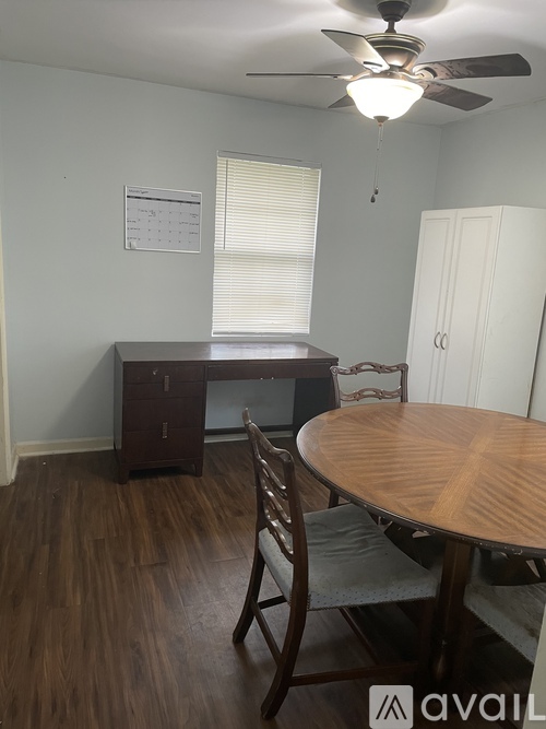A room with a table and chairs and a fan.