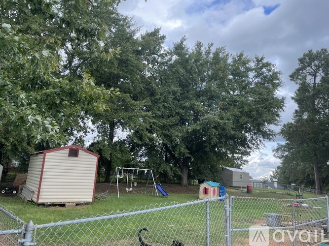 A backyard with a fence, a shed, and a playground.