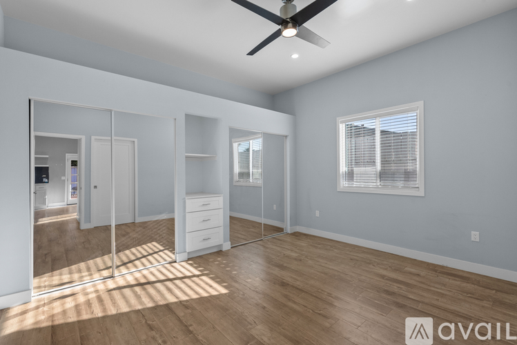 A spacious room with a ceiling fan and wooden flooring.