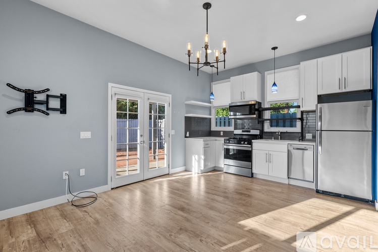 A modern kitchen with wooden floors and stainless steel appliances.