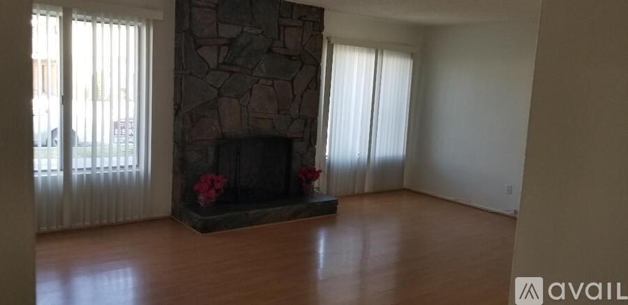 A living room with a stone fireplace and wooden floors.
