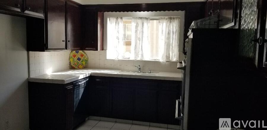 A kitchen with dark wood cabinets and a white sink under a window.