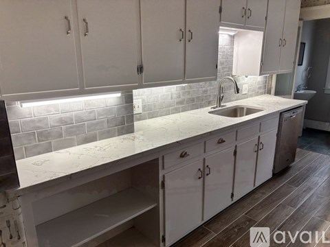 A kitchen with white cabinets and a marble countertop.