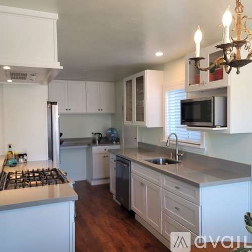 A kitchen with white cabinets and a stove top oven.