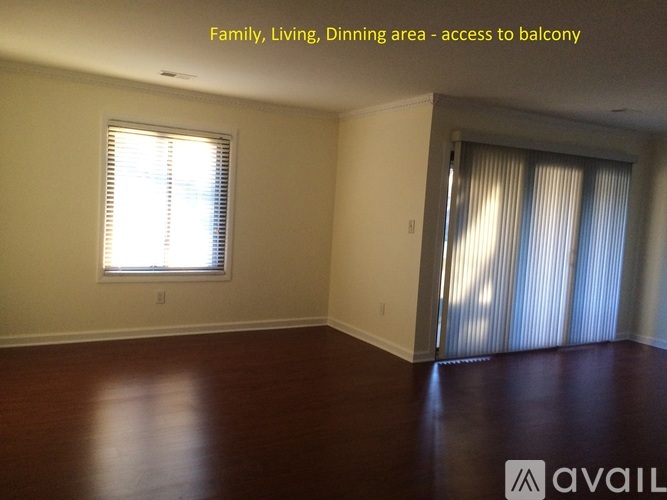 A spacious room with a window and a sliding door leading to a balcony.
