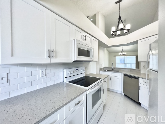 A modern kitchen with white cabinets and appliances.