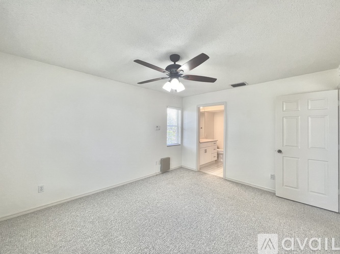 A spacious room with a ceiling fan and carpeted floor.
