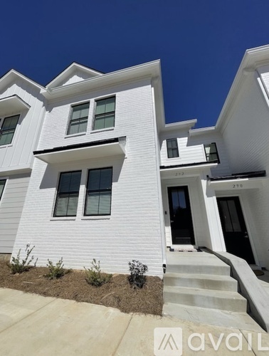 A white two-story house with a black door and windows.