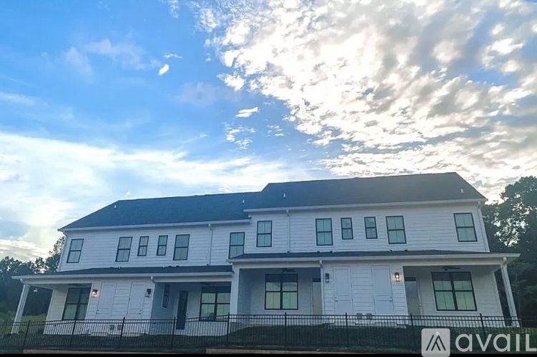 A white house with a black roof and a sign that says "available" in front of it.