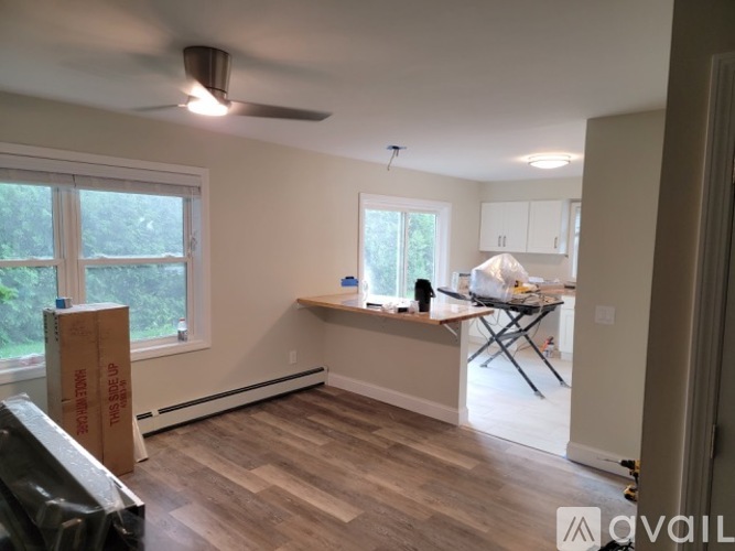 A room with a ceiling fan and a window with a view of trees.