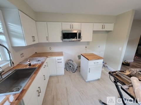 A kitchen with white cabinets and a wooden island.