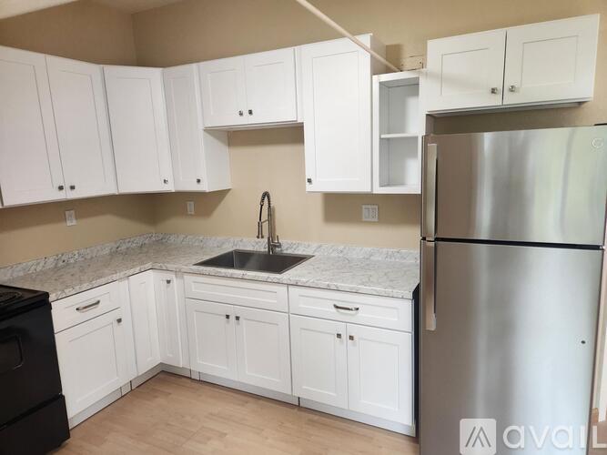 A kitchen with white cabinets and a stainless steel refrigerator.