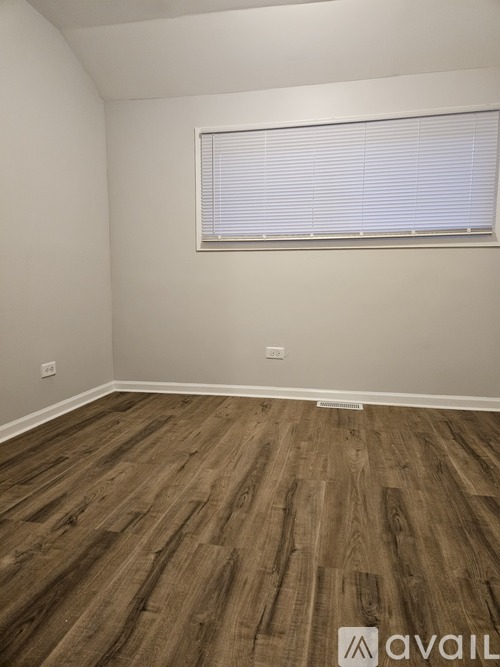 A room with wooden flooring and a window with blinds.
