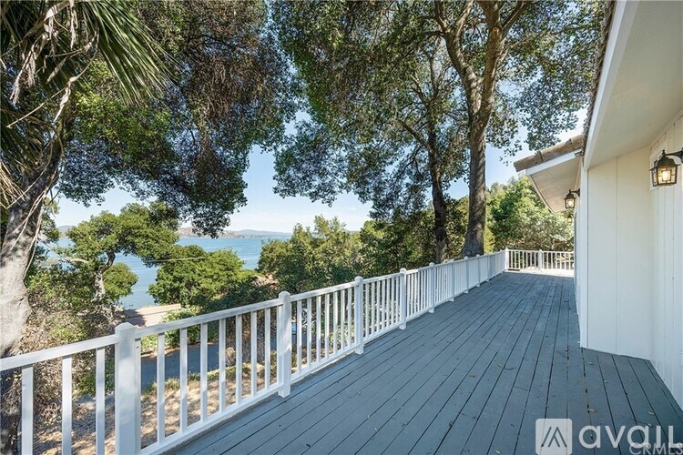 A wooden deck with a white railing overlooks a body of water.