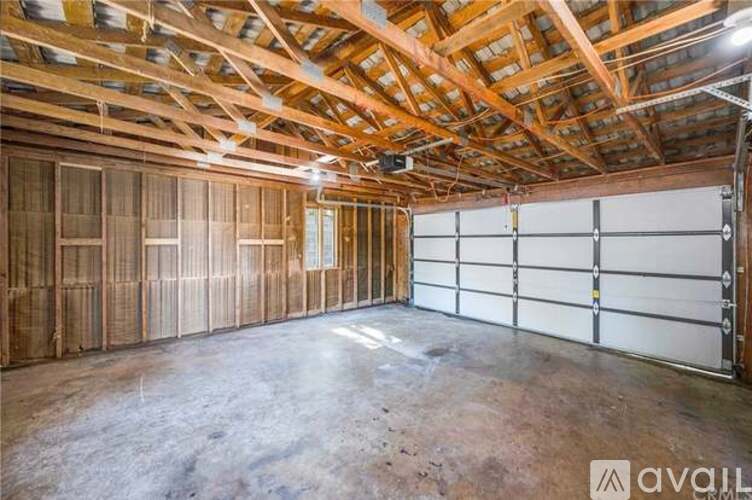 A spacious garage with wooden walls and ceiling, and a white garage door.