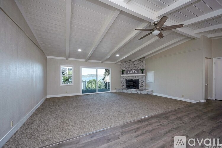 A spacious living room with a fireplace and a ceiling fan.