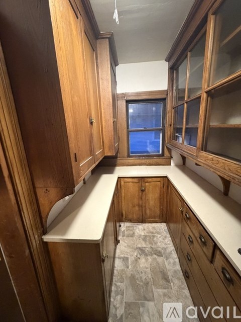 A kitchen with wooden cabinets and a marble floor.