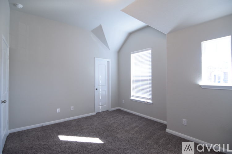 A spacious room with a carpeted floor and a large window with blinds.