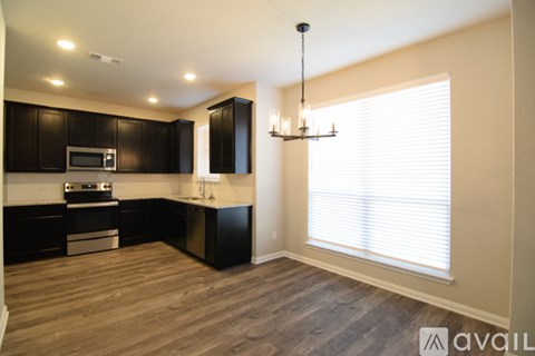 A modern kitchen with dark brown cabinets and a wooden floor.